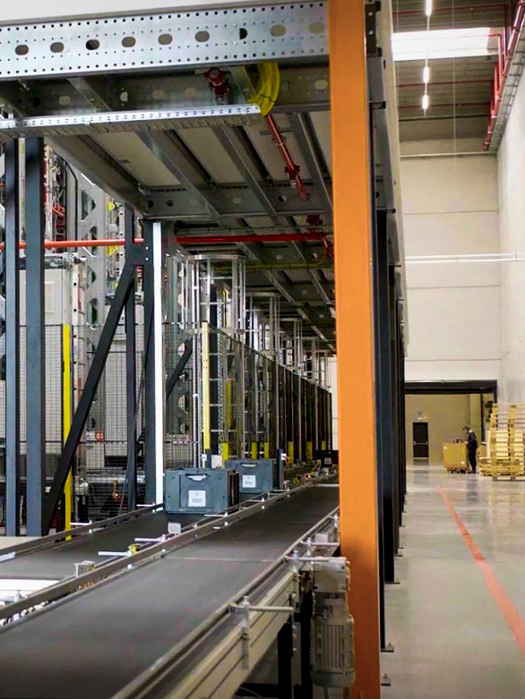 Worker crossing near a warehouse conveyor system with safety barriers in place