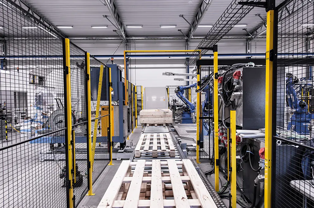 Automated palletising line with robotic arms and pallets in safety zone