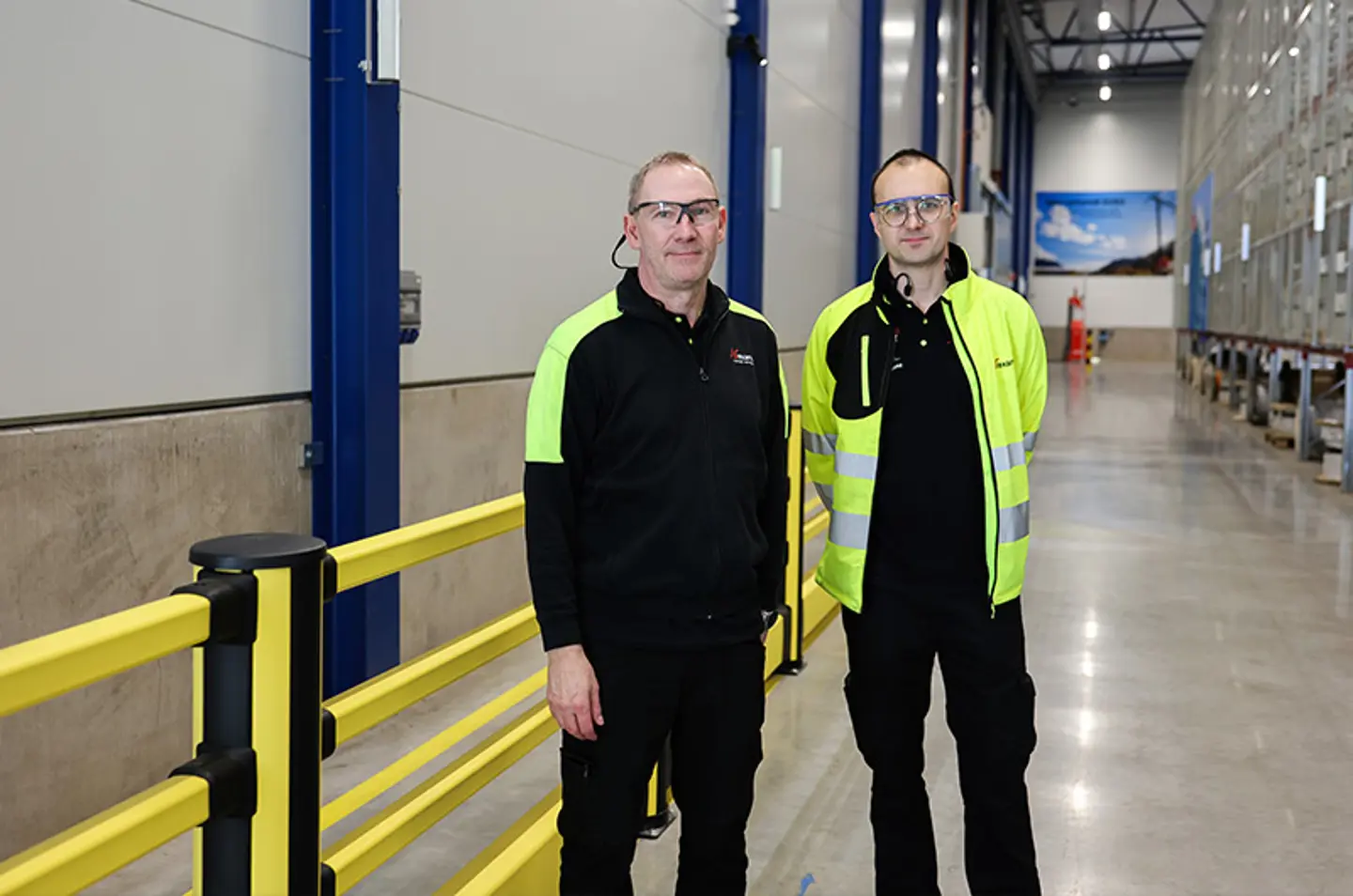 Patrick Erlandson and Peter Kebke in front of a pedestrian barrier in a warehouse