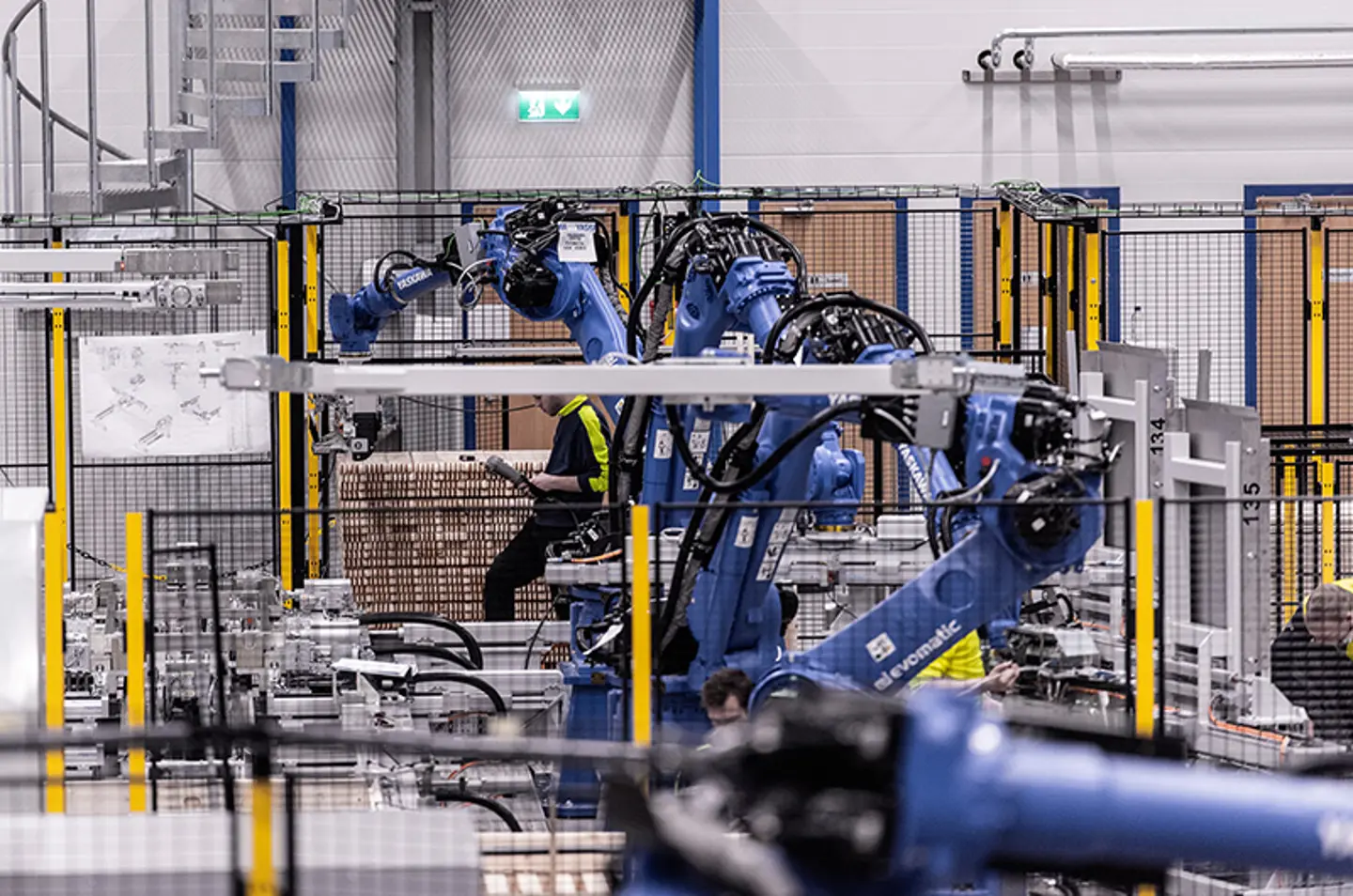 Industrial robotic arms palletising goods inside secured automation cell