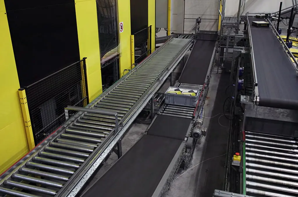 Automated warehouse sortation system with conveyors and safety fencing for high-speed logistics
